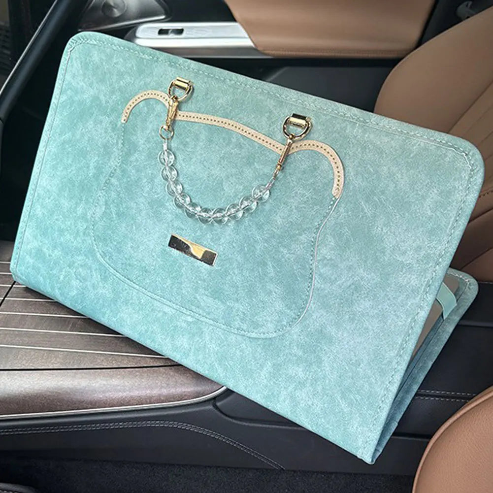 A teal laptop briefcase with a leather trim and silver chain strap is placed on a car seat.