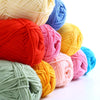 A collection of brightly colored soft 4-ply milk cotton yarn skeins in shades of red, pink, yellow, and blue.