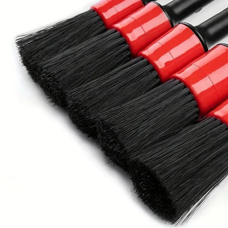 A set of red and black car detailing brushes with soft bristles for interior and wheels.
