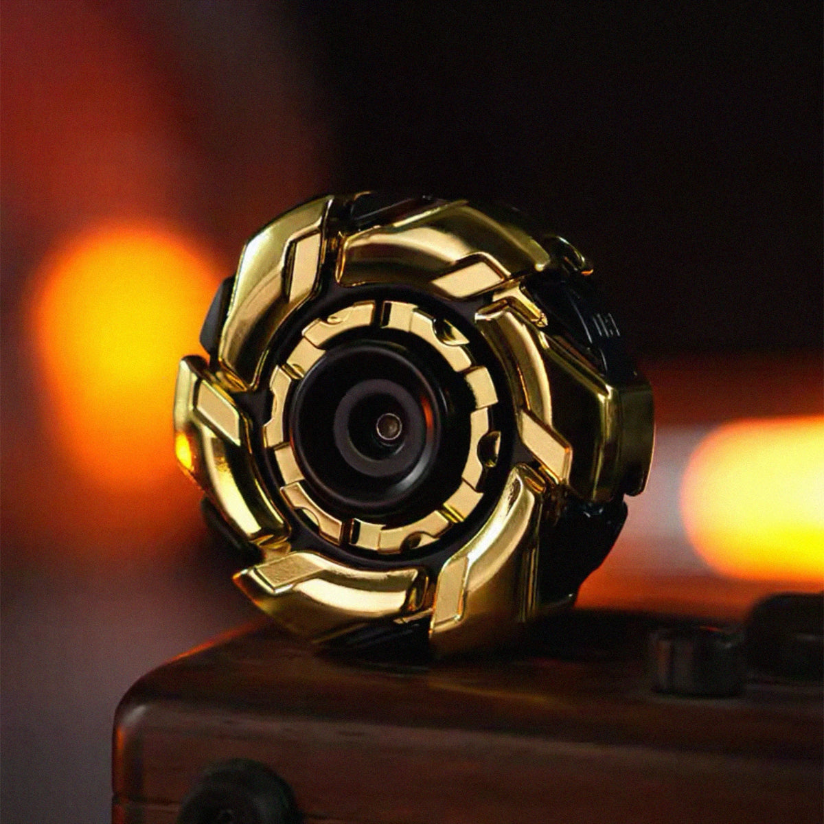 A close-up of a gold and black fidget spinner with a camera lens design resting on a wooden surface.