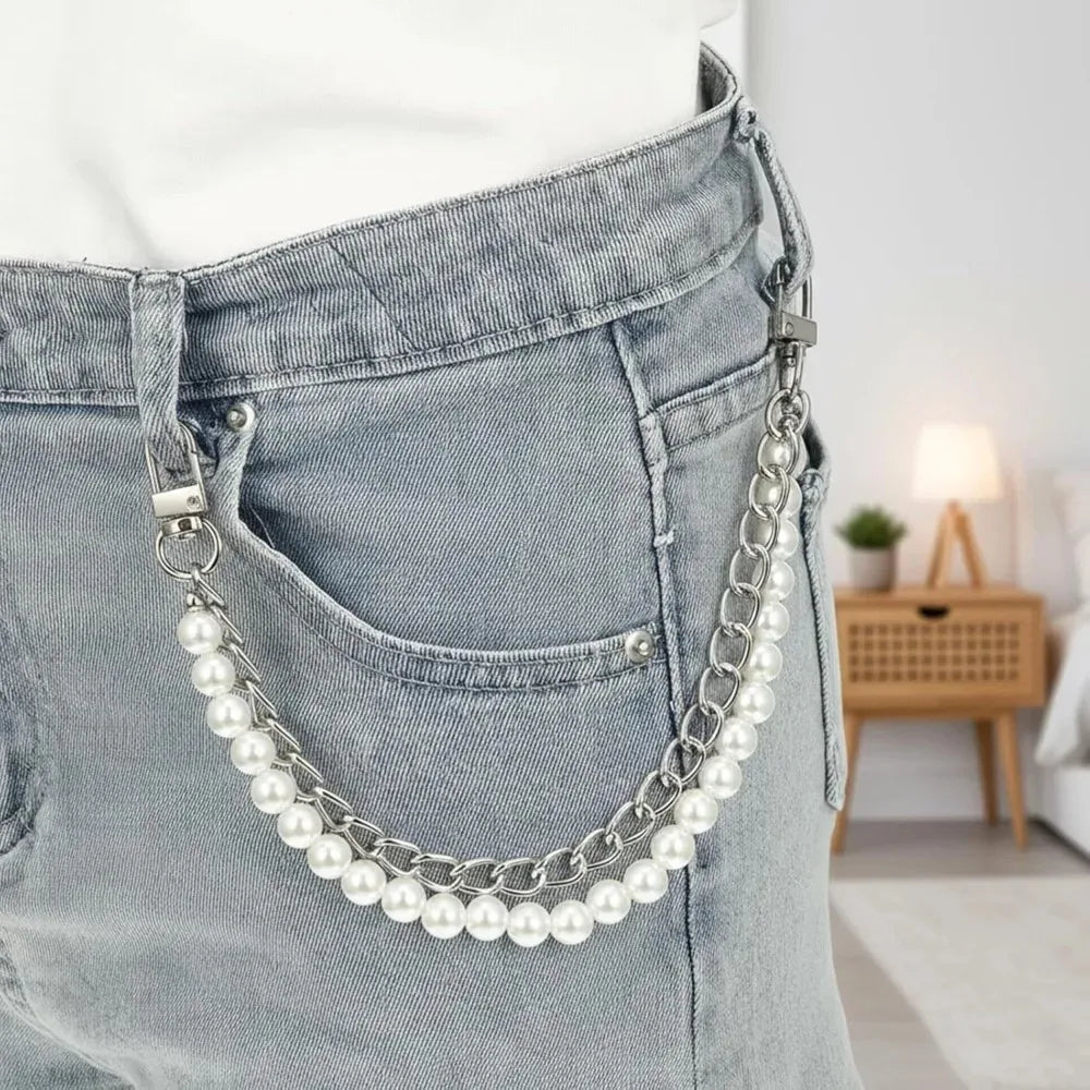 A silver pearl and gold chain purse hanging from the pocket of light gray denim jeans.