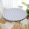 A round table covered with a light blue and white patterned waterproof tablecloth in a bright room.