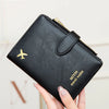 A hand holds a black leather travel wallet with a gold zipper and an airplane pattern, designed for RFID protection.