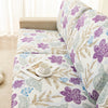 A floral elastic sofa cover featuring purple and green botanical patterns on a light-colored fabric.