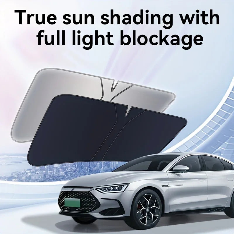 A black foldable car windshield sunshade is shown in use on a silver sedan.