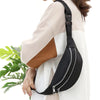 A black nylon waist pack with a zipper is worn on a light-colored top.