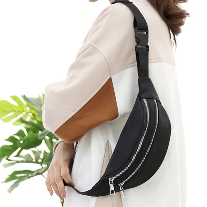 A black nylon waist pack with a zipper is worn on a light-colored top.