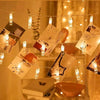 String lights with small glass photo clips hanging in a warm, indoor setting.