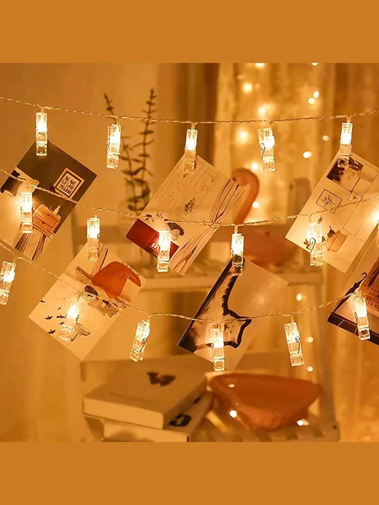String lights with small glass photo clips hanging in a warm, indoor setting.