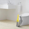 A yellow pumice stone toilet and bathroom cleaning brush with a handle standing next to a white toilet.
