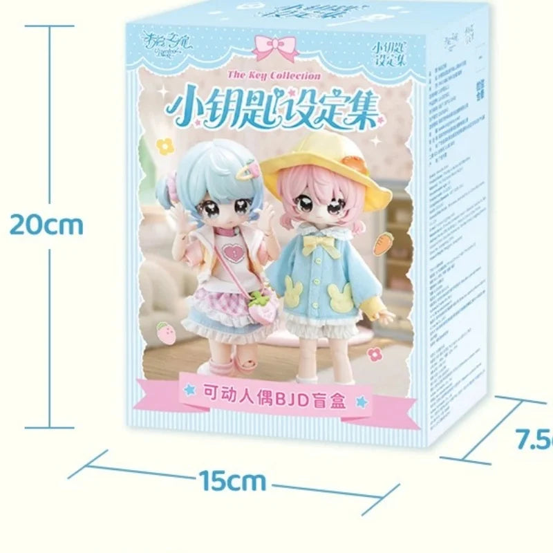 A box of The Key Collection featuring two small articulated BJD collectible figurines with light blue and pink hair and outfi