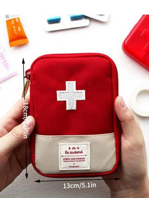 A red compact travel medicine organizer bag with a white cross emblem is held in a person's hand.