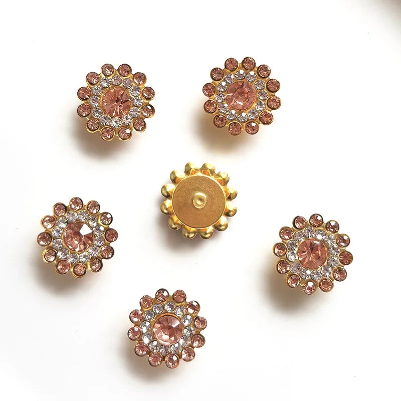 Five clusters of rose gold and clear rhinestones shaped like flowers on a white background