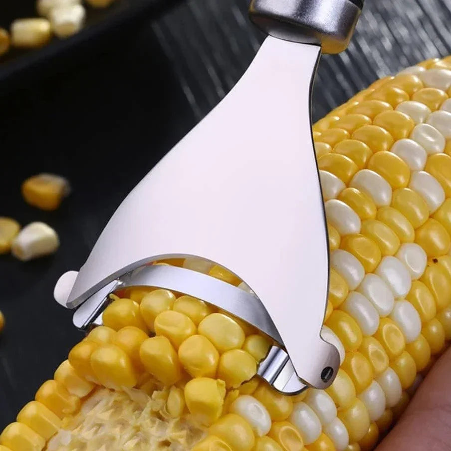 A stainless steel corn peeler is shown peeling corn kernels from a cob.