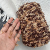 A close-up of brown and beige hand-dyed variegated cotton blend yarn for knitting and crochet.