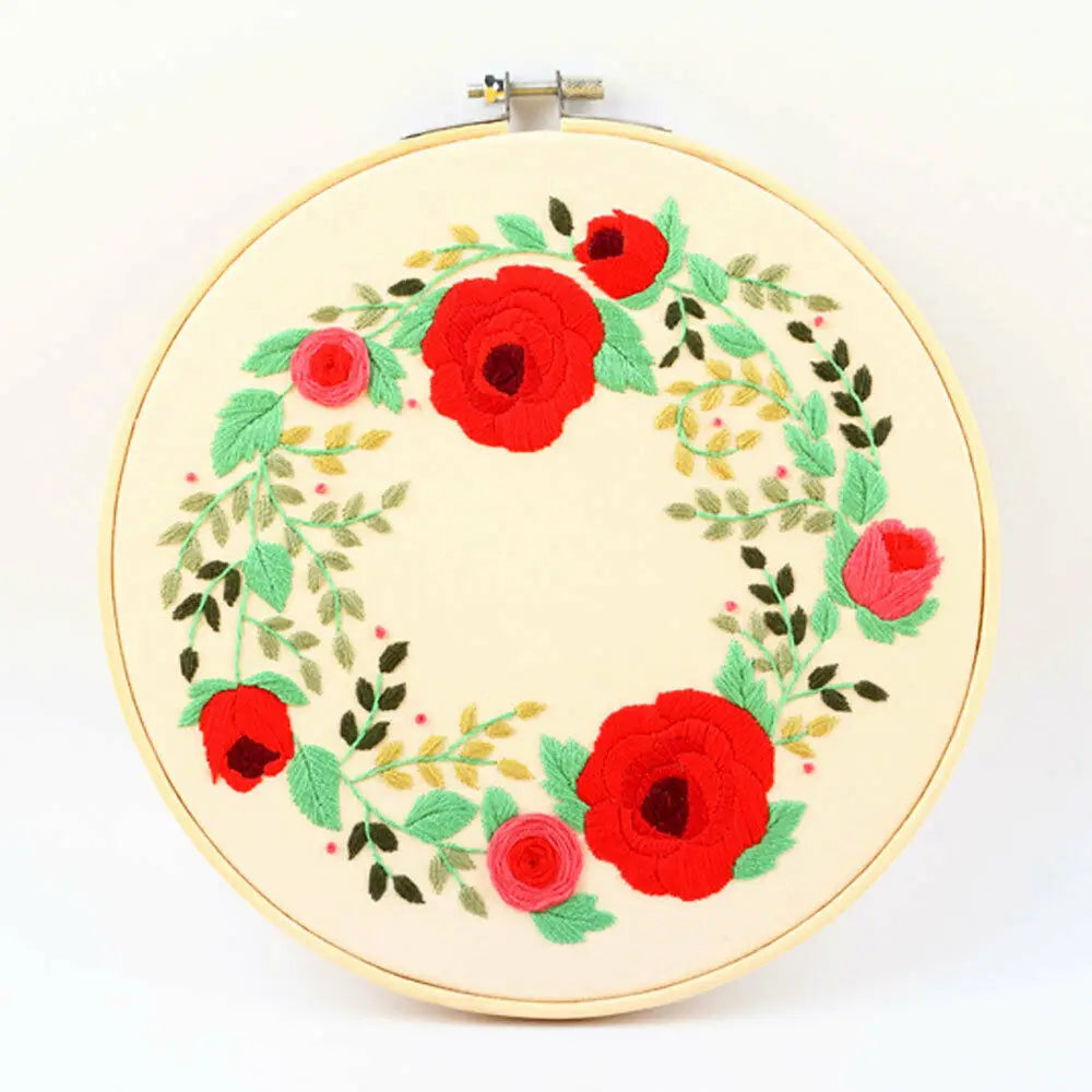 A round embroidery hoop featuring a red and green floral wreath design.