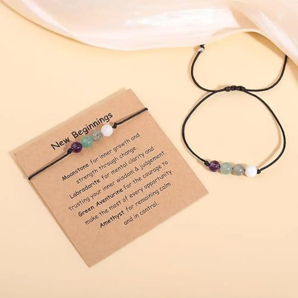 Schwarzer Armband mit grünen und weißen Heilsteinen, präsentiert auf einer beige Karte.