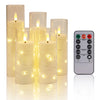A set of tall, cylindrical LED candles with twinkling string lights and a remote control for lighting.