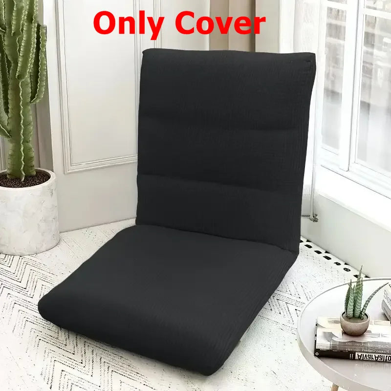 A black foldable floor sofa cover for a single seat or lounger placed on a white tiled floor near a window.