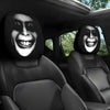A pair of black car headrest covers featuring stylized, grinning faces are visible in a vehicle interior.