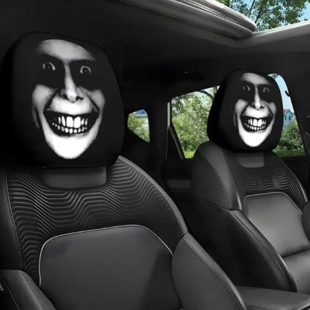 A pair of black car headrest covers featuring stylized, grinning faces are visible in a vehicle interior.