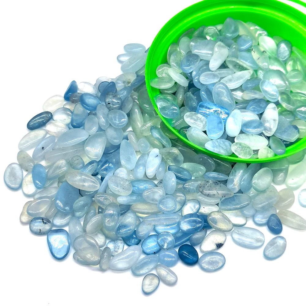 A pile of tumbled blue and clear quartz crystal stone chips in a green bowl.