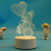 A glowing wireframe teddy bear night light lamp displayed on a white base against a blue background.