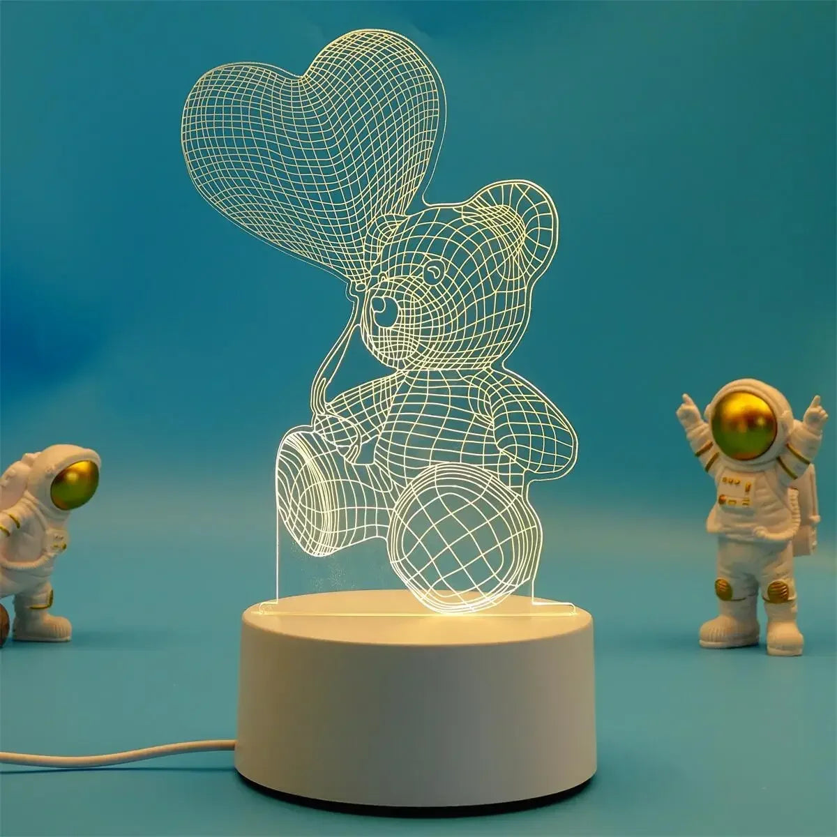A glowing wireframe teddy bear night light lamp displayed on a white base against a blue background.