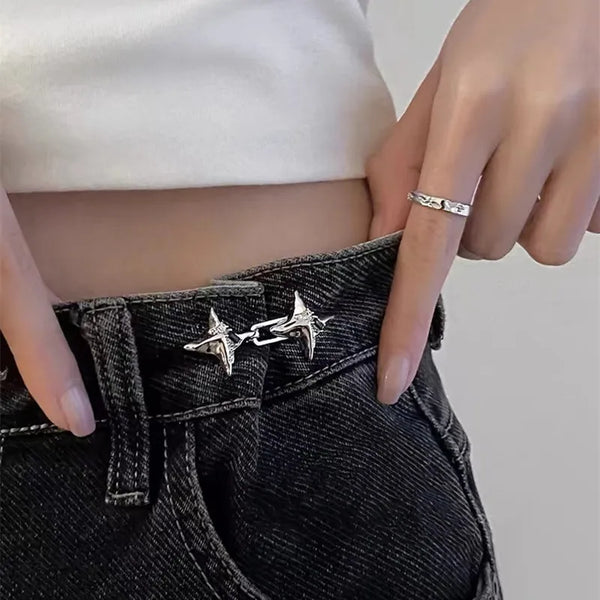 Nahaufnahme einer Hand, die einen silbernen Gürtel zum Engziehen an schwarzen Jeans trägt.