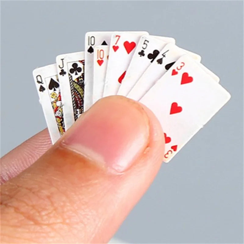 A hand holds a fan of mini playing cards showing various numbered and face cards.