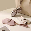 A light pink PU leather glasses case with a retro lychee pattern and a brown leather strap is displayed on a beige surface.