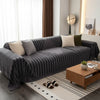 A dark gray woven sofa cover with a vertical striped pattern is displayed on a light rug in a modern living room.