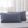 A set of two solid blue-gray microfiber pillowcases resting on a light gray surface.