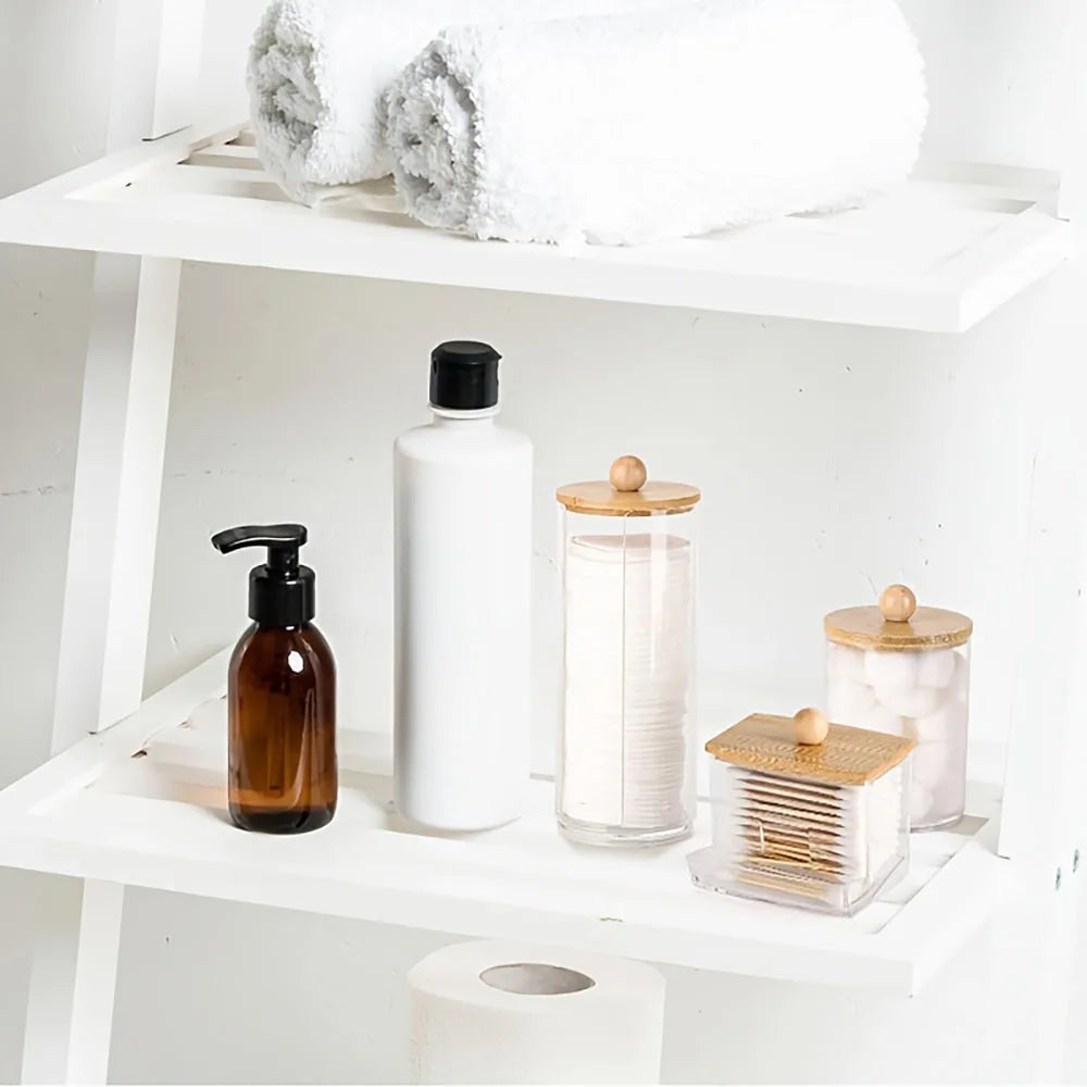 A white bathroom organizer set featuring a glass bottle, a white bottle, and a wooden soap dispenser on a shelf.