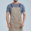A man wearing a beige waterproof adjustable kitchen apron over a blue t-shirt.