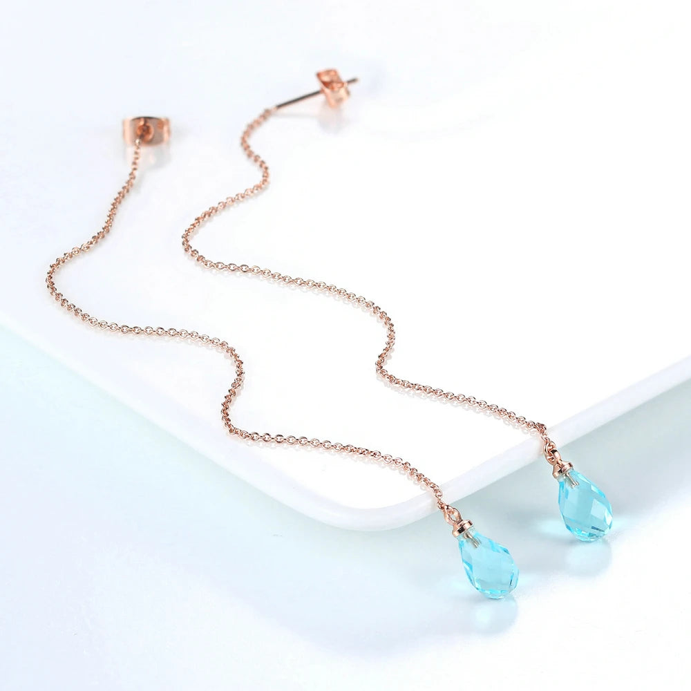 Collar de cadena tono dorado con pendientes colgantes de circonita cúbica en forma de lágrima sobre fondo blanco