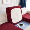 A close-up of a deep red stretch jacquard sofa cover with a light cream back and blue accents.