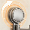 A close-up of a metallic suction cup hook mounted on a wall, showing its round design and mounting mechanism.