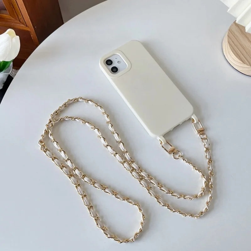A white smartphone is shown with a gold-colored chain strap lying on a white surface.