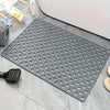 A gray anti-slip shower mat with numerous massage points and drainage holes placed on a tile surface.
