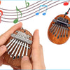 A hand holds a wooden kalimba thumb piano with metal tines, set against musical staff lines.