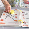 A child is using a yellow pen to trace lines in a reusable magic tracing workbook for kids.