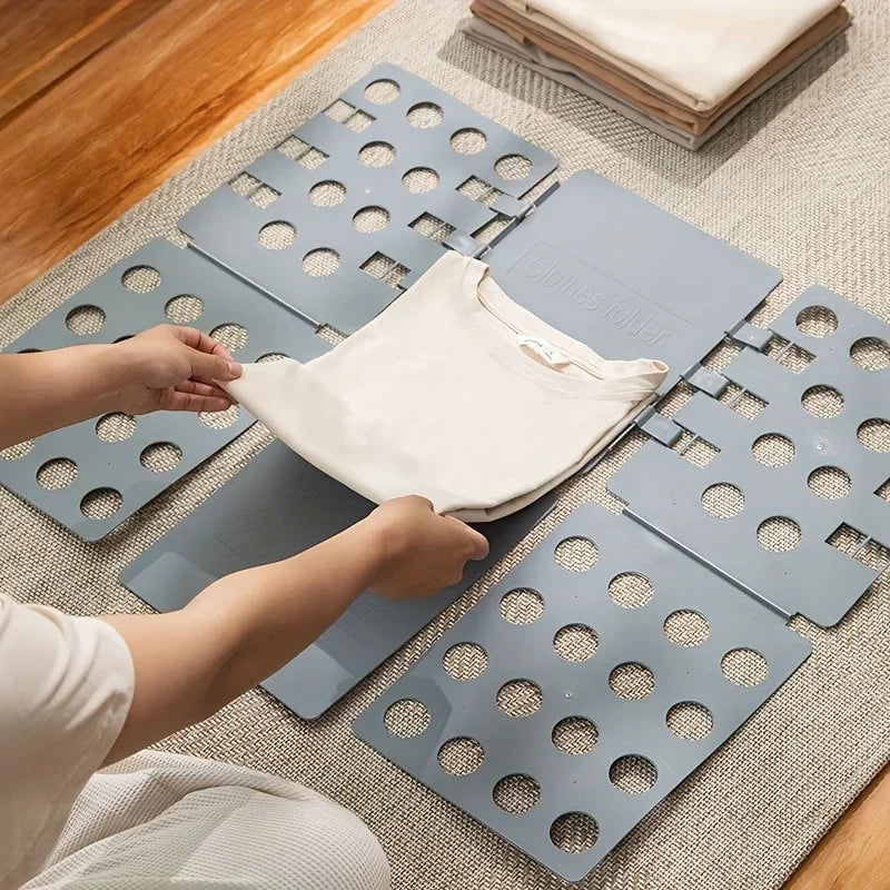 Hands are folding a white garment onto a portable clothes folding board with multiple circular holes.