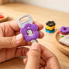 A hand holds a silver key with a purple flower silicone cover, demonstrating colorful key protectors.