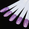 A set of clear acrylic false nail tips with purple glitter finish displayed on a black background.
