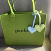 A lime green tote bag with a light blue and pale green heart-shaped keychain charm.