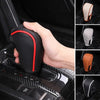 A hand is holding a black gear shift knob cover with red accents, showing its texture and fit.
