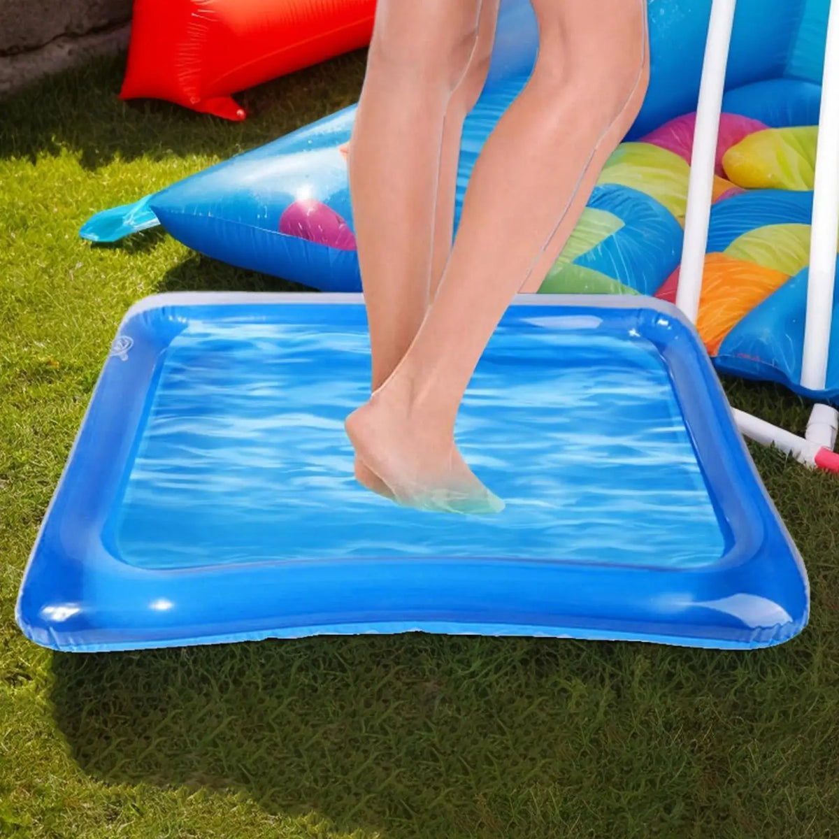 A person's bare feet are soaking in a blue inflatable foot soaking basin on green grass.