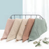 Five soft cotton gauze burp cloths in pastel shades laid out on a black wire rack.