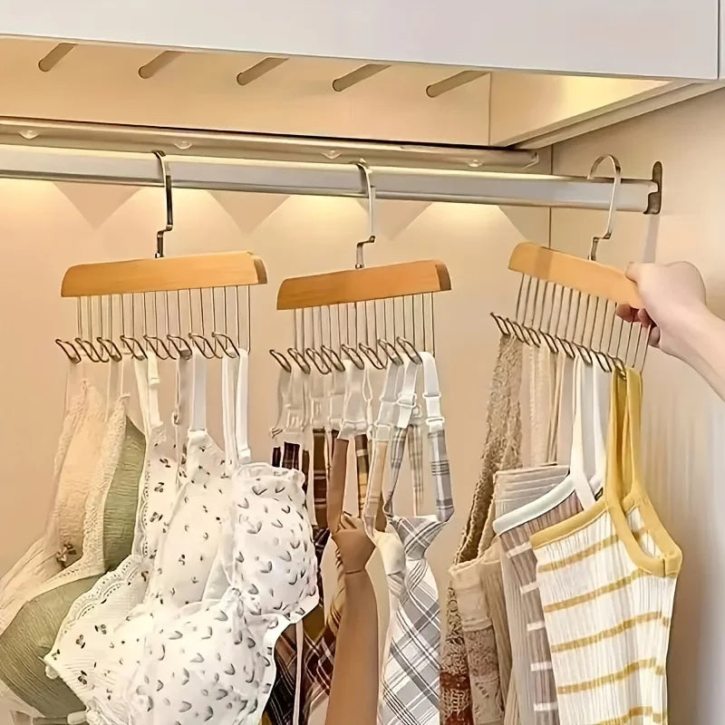 A wooden hanging clothes rack displaying various garments on multiple hooks.